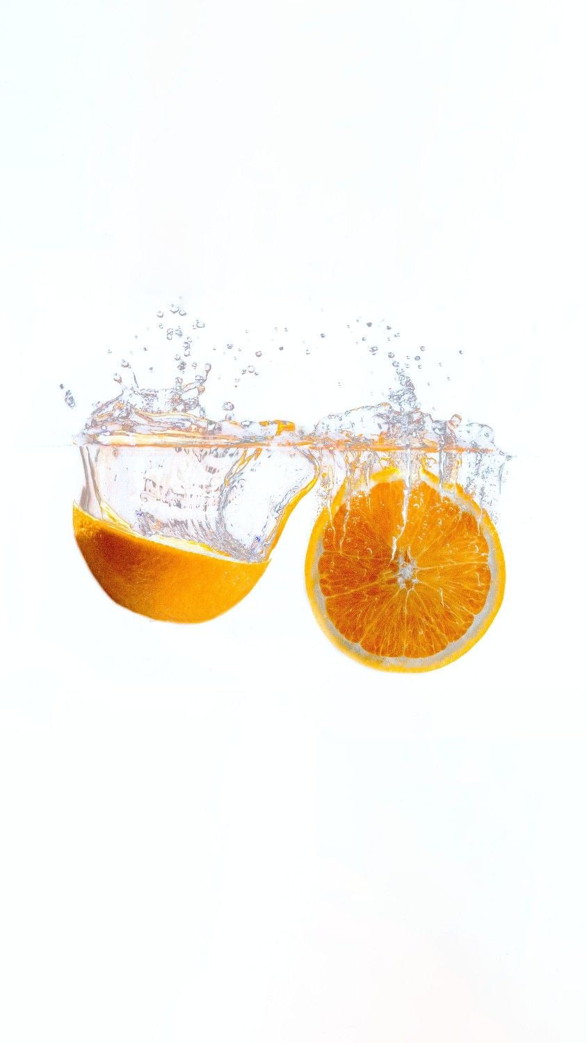 Fresh orange slices splashing into clear water on a white background