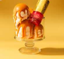 Red and gold Arabian oud perfume bottle in a glass dish with caramel-drizzled scoops.