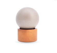 Minimalist oud diffuser with a round stone top and wooden base on white background