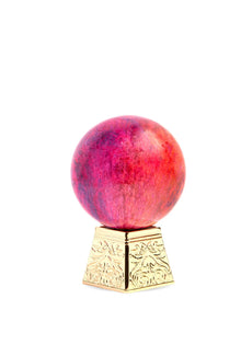 Ornate gold stand with a vibrant red and purple marble sphere, luxury home decor accent.