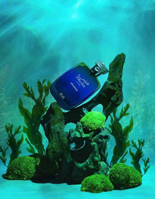Blue Arabian oud perfume bottle labeled Hawas Atlantis underwater with green moss and seaweed.