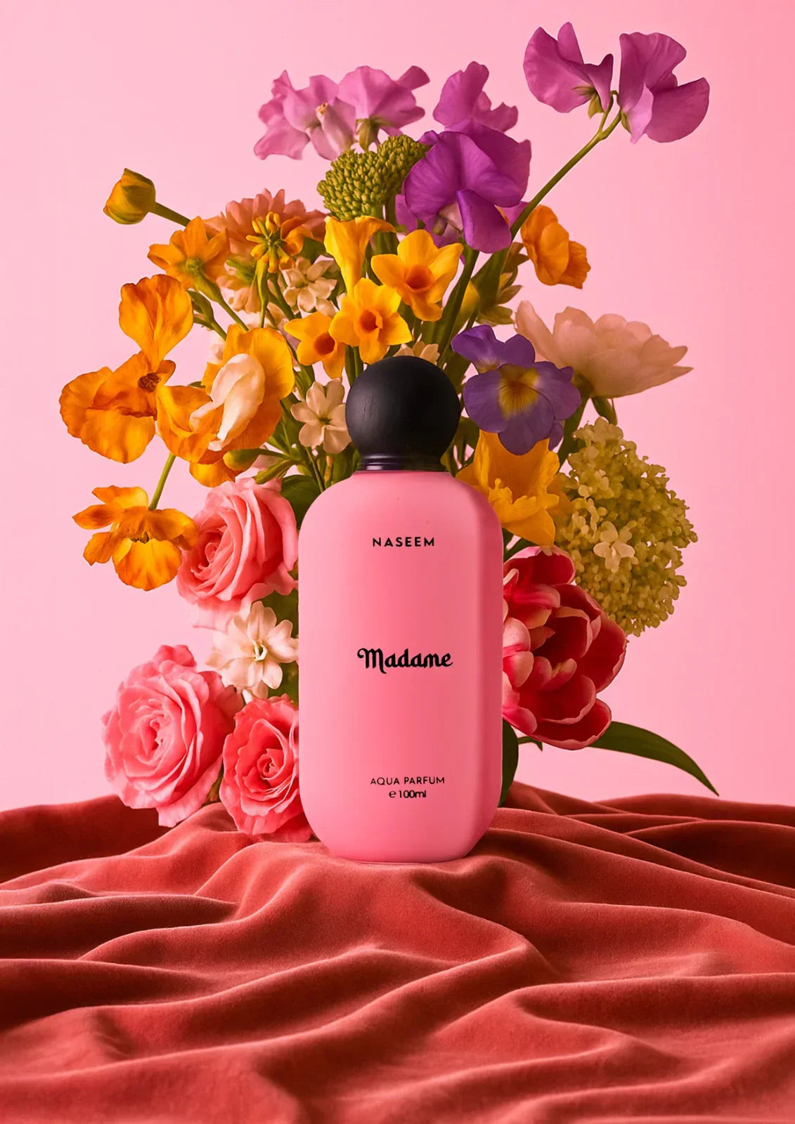 Pink Madame perfume bottle with black cap in front of colorful flowers on pink velvet