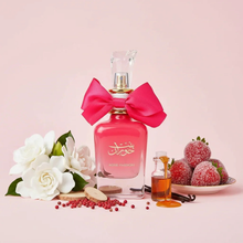 Pink Arabian oud perfume bottle with bow, surrounded by white flowers, sugared strawberries, and fragrance ingredients on a light pink background.