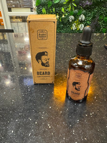 Naseem beard grooming oil bottle and box on black countertop with leafy background