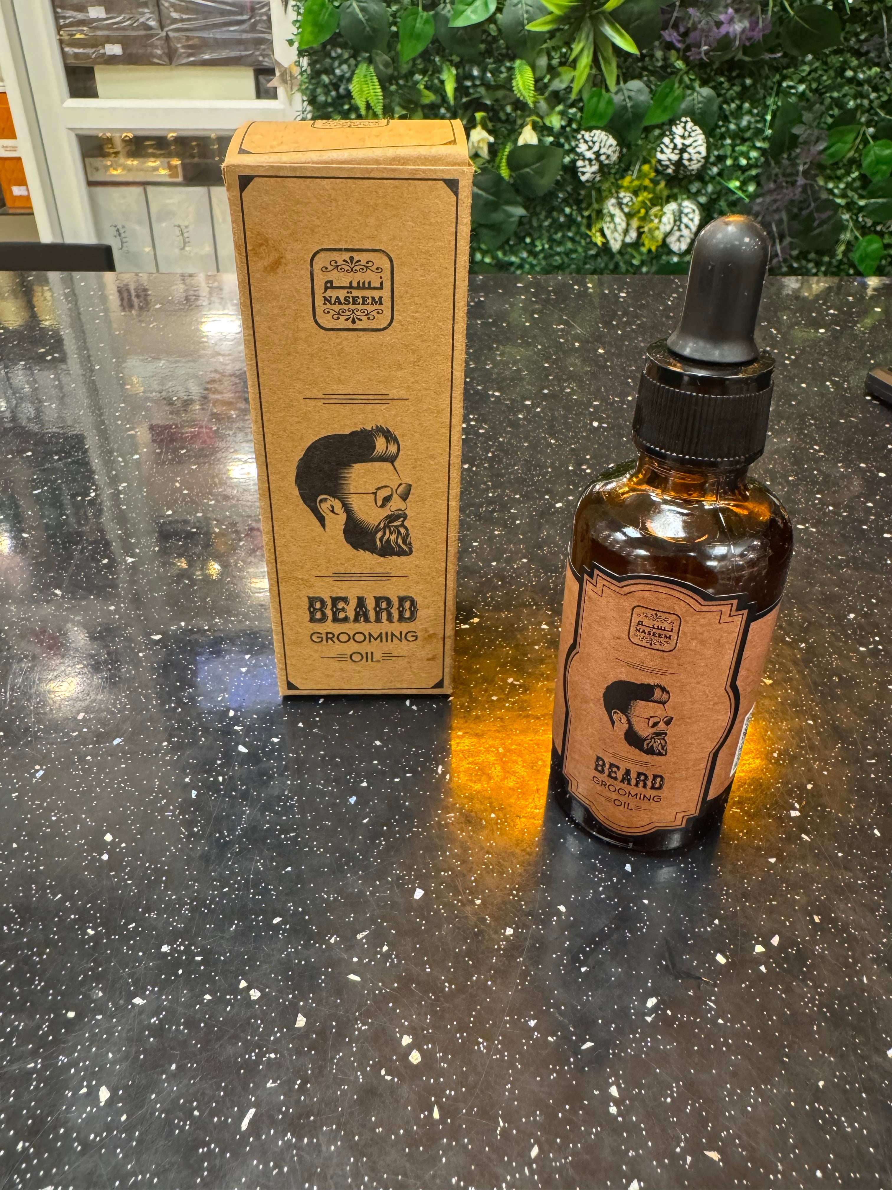 Bottle and box of 'Beard' grooming product on a reflective surface with greenery in the background