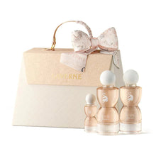 Elegant perfume gift set with four glass bottles, cream textured box, and decorative bow.