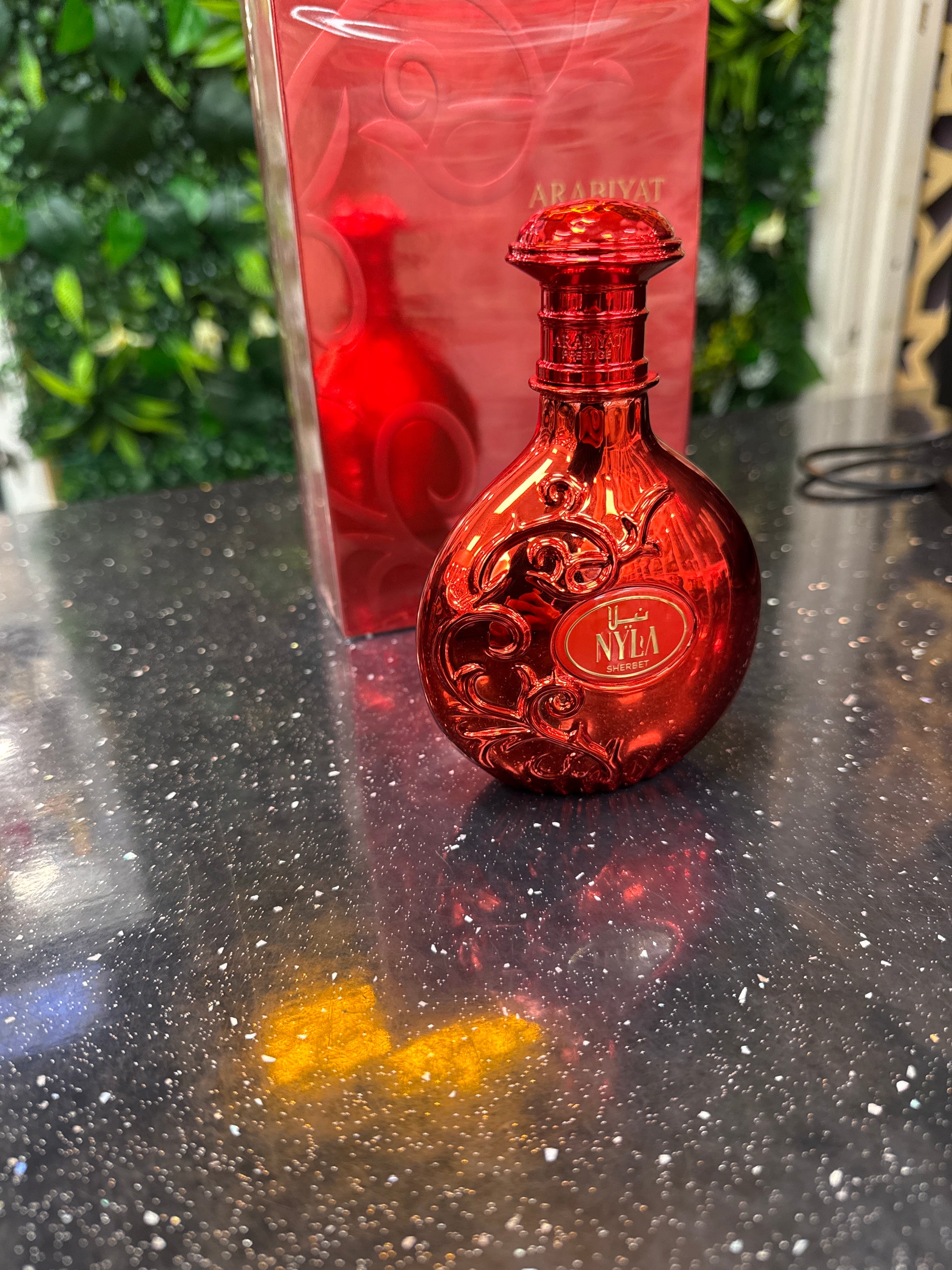 Red bottle with decorative cap on a reflective surface