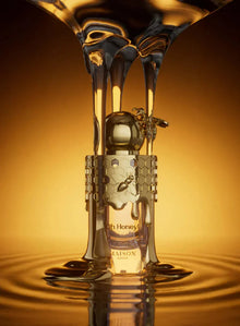 Honey-themed perfume bottle with honeycomb and bee design against a golden background.