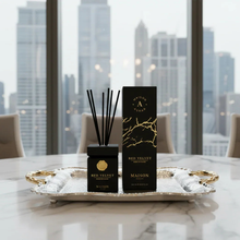 Luxury reed diffuser set with black and gold packaging on a silver tray, modern city view.