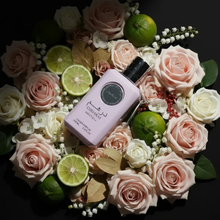 Dirham Wardi pink perfume bottle with roses, limes, and white flowers on a black background