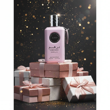 Dirham Wardi pink Arabian perfume bottle on stacked gift boxes with glittery dark background