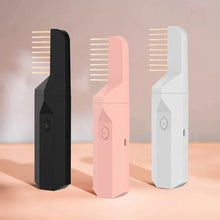 Three electric beard combs in black, pink, and white, standing upright on a light surface.