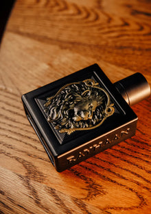 Luxurious black oud perfume bottle with lion emblem and Rayhaan text on wooden surface