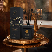 Luxury Arabian oud reed diffuser set in black and gold on decorative tray with brass pitcher.