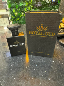 Luxury Royal Oud perfume bottle and box on speckled counter, green plant wall in background