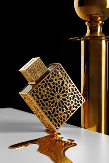 Luxury Arabian oud perfume bottle with intricate gold pattern, spilling fragrance on white surface