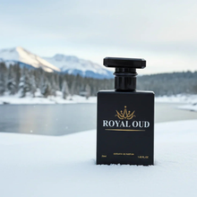 Royal Oud perfume bottle in snow with snowy mountains and pine trees in the background