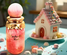 Pink and gold perfume bottle labeled Marshmallow Blush beside marshmallow candy house