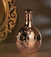 Elegant rose gold Arabian oud perfume bottle with ornate floral design, luxury fragrance