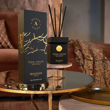 Maison Asrar Pink Crush reed diffuser and box set on elegant gold table in cozy living room.