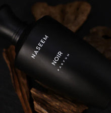 Naseem Noir Parfum black bottle with oud wood pieces, luxury Arabian oud perfume.