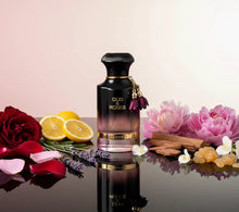 Oud & Roses perfume bottle surrounded by rose petals, lemon slices, lavender, peonies, and spices.