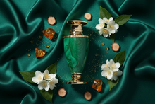 Luxury Arabian oud perfume bottle with gold accents, surrounded by white flowers, wood, and amber on emerald green silk.