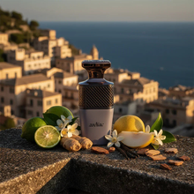 Elegant perfume bottle labeled 'zodiac' with fresh lime, ginger, lemon, vanilla, and flowers on stone ledge, scenic coastal town in background