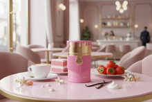 Strawberry-themed oud perfume in pink and gold bottle on café table with strawberries, cake, and vanilla.