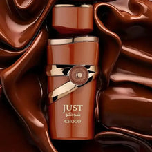 Close-up of Just Choco 100ml EDP perfume bottle with gold wrap and floral design, surrounded by brown satin fabric, in a cosmetics and fragrance category