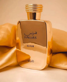 Gold Hawas Elixir perfume bottle with Arabic script on a golden satin background