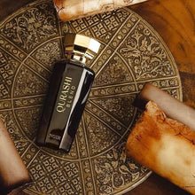 Qurashi Blend oud perfume bottle with gold cap on ornate circular tray, vintage scrolls nearby