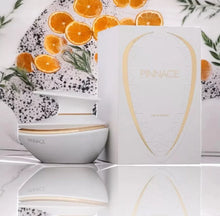 Elegant Pinnace eau de parfum bottle and box with citrus slices and green herbs in background