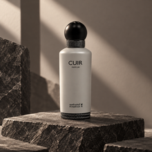 Al Majed Oud Cuir Parfum grey bottle on a charcoal stone podium with architectural shadows
