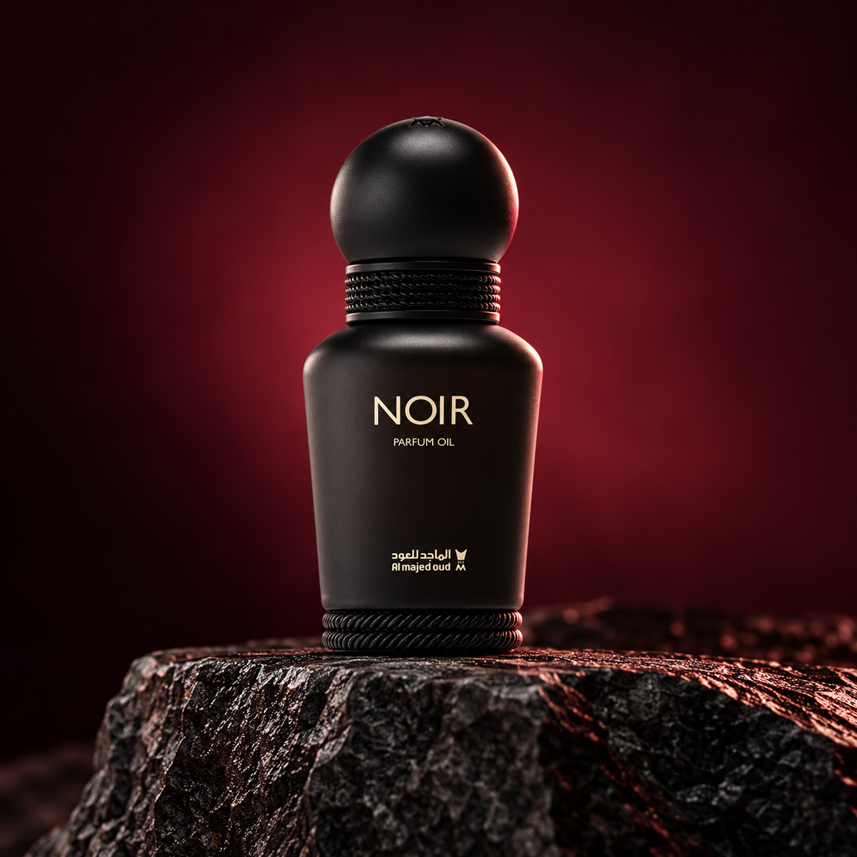Noir Perfume Oil 15ml matte black bottle on dark stone with burgundy rim lighting