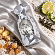 Overhead Marwa Extrait bottle on silver silk and pale stone with bergamot tea ginger and incense; design may vary