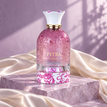 Lattafa Petra Viola pink bottle on a lilac stone plinth with ivory silk and soft window light