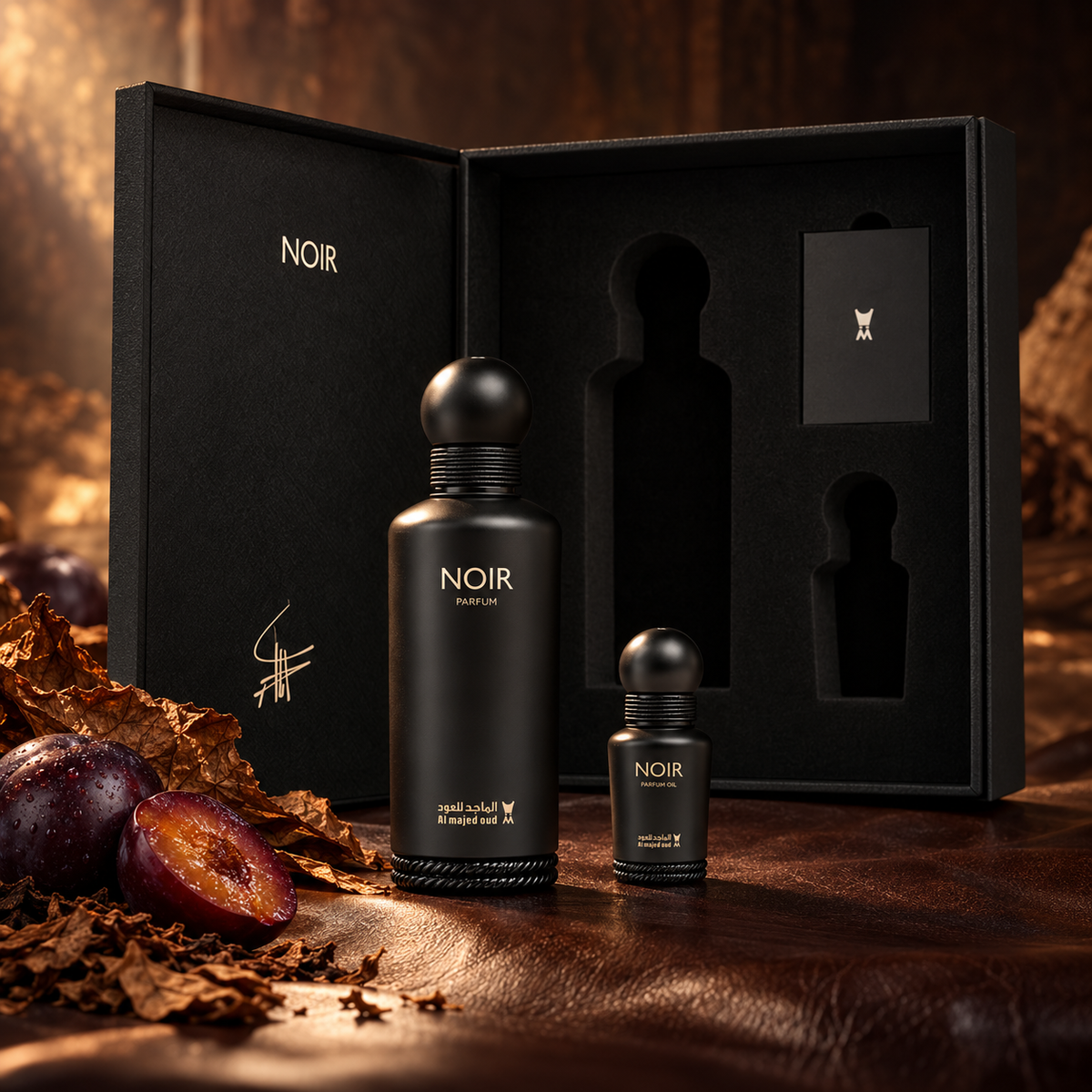 Noir Parfum and perfume oil with the original open gift box, plum and tobacco-leaf props on dark leather