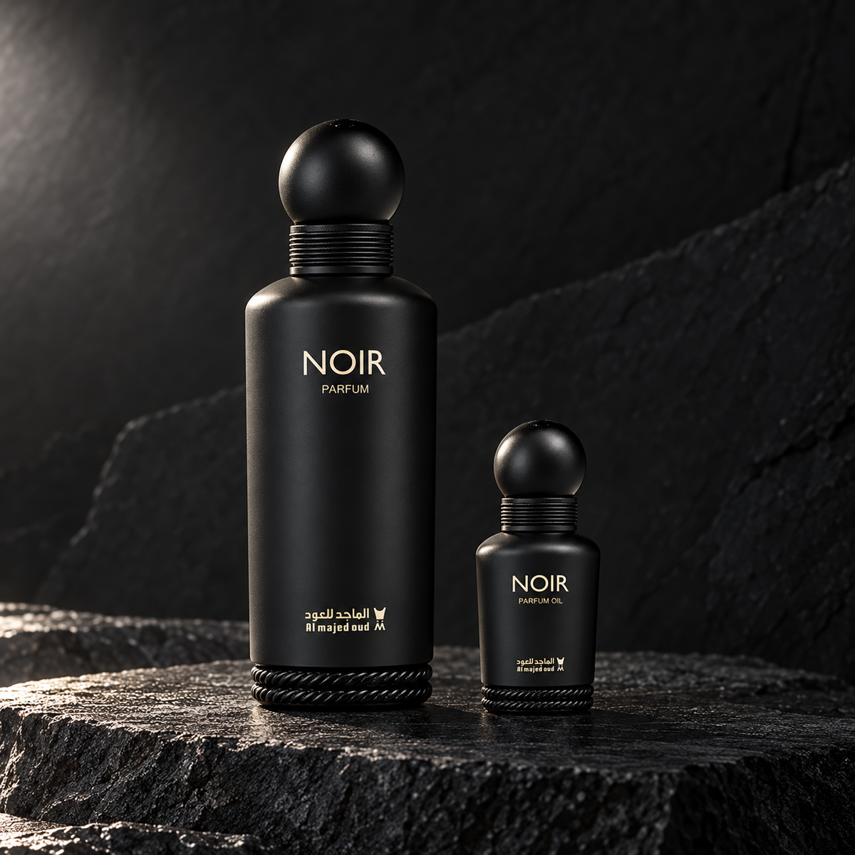 Al Majed Oud Noir 150ml Parfum and 15ml perfume oil bottles on dark charcoal stone