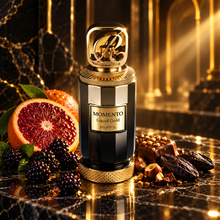 Momento Liquid Gold bottle with blackberries blood orange praline and tonka in golden light